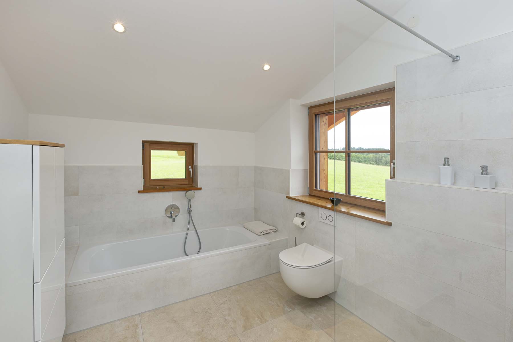 Hauser Häuser_Holzhaus KfW 40 Plus in Hopfen am See (14) Badezimmer mit Badewanne und Fenstern