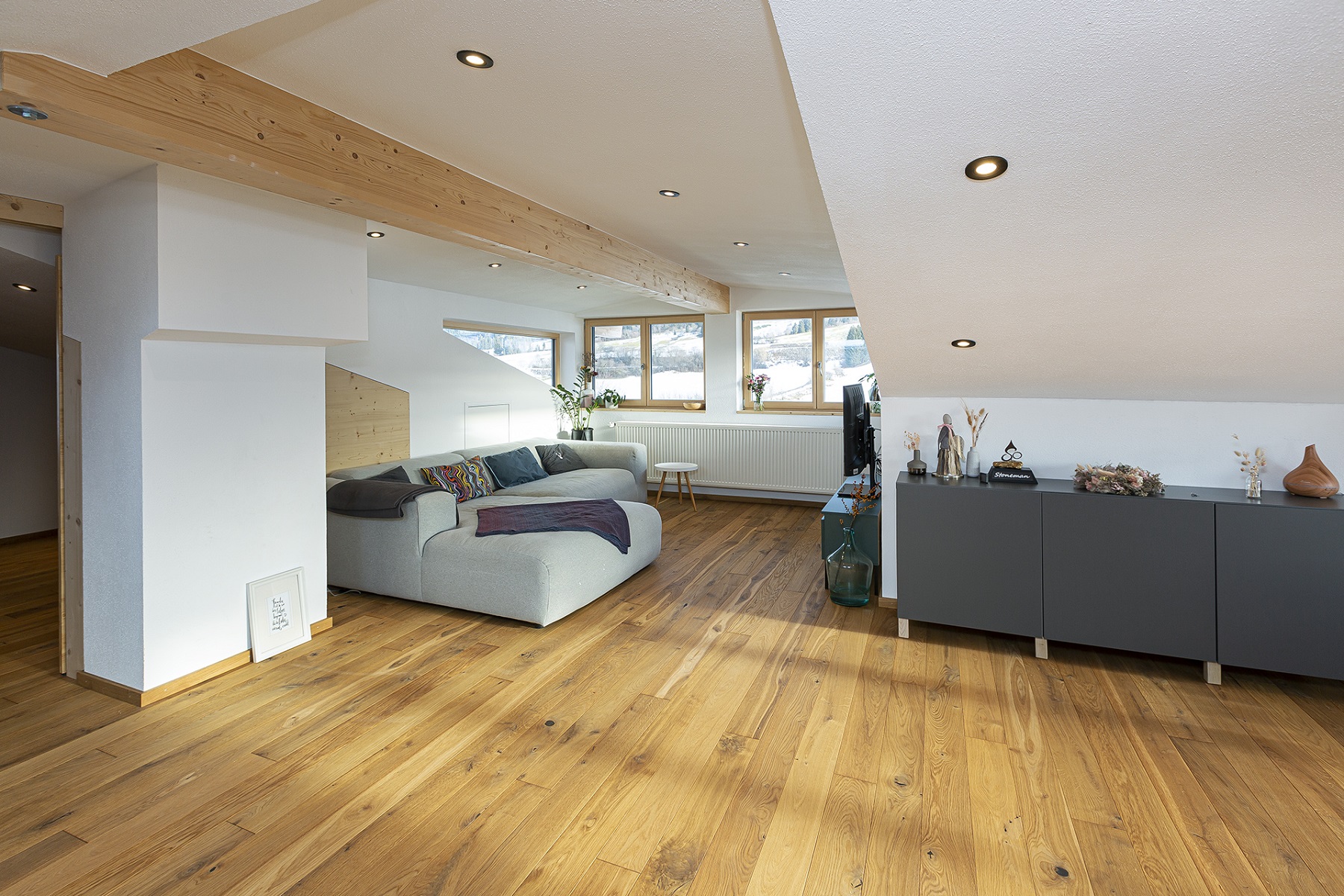 Offener Wohnbereich mit Dachschräge, Holzbalken und Holzfussboden