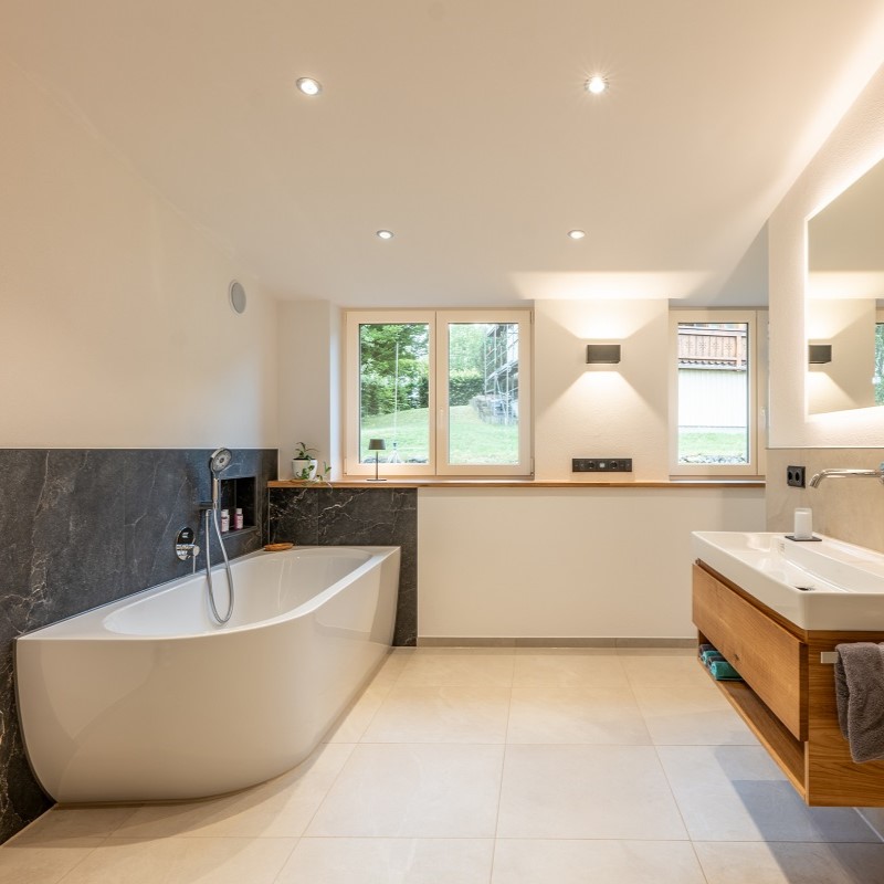 Modernisiertes Bad mit freistehender Wanne, Fensterfront und Waschbecken